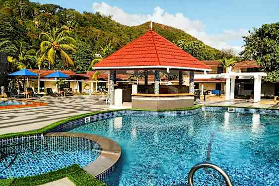 Swimmingpool med et poolbarområde og omkringliggende tropiske træer. (AI-genereret tekst)