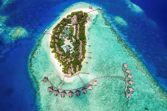 Luftfoto af en tropisk ø med bygninger omgivet af turkisblåt vand. (AI-genereret tekst)