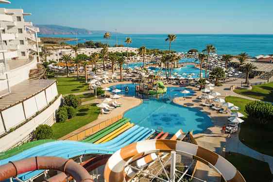 Udsigt over hotellets pools og vandrutsjebaner nær havet. (AI-genereret tekst)