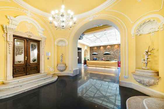 Indgangsområde med klassiske arkitektoniske detaljer og reception i en lys atmosfære. (AI-genereret tekst)