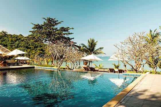 En infinitypool ved en strand med liggestole og parasoller i baggrunden. (AI-genereret tekst)