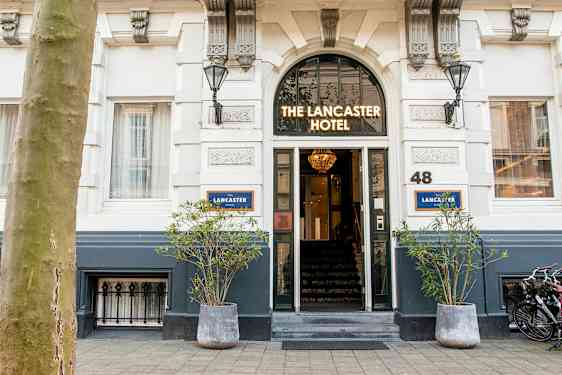 Indgang til et hotel med skiltet 'The Lancaster Hotel' over døren. (AI-genereret tekst)