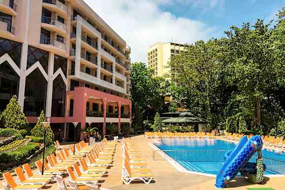 Hotelbygninger ved en udendørs pool med liggestole og vandrutsjebane. (AI-genereret tekst)