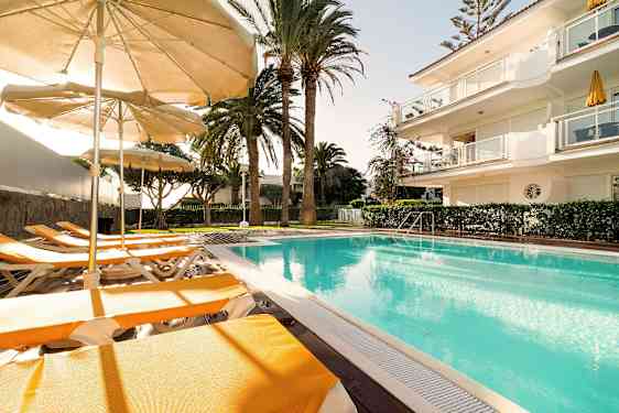 Udendørs pool med liggestole og parasoller i solskinsvejr. (AI-genereret tekst)