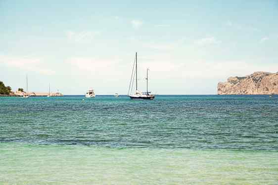 En klar blå himmel over en havudsigt med sejlbåde på vandet og en klippekyst i baggrunden. (AI-genereret tekst)