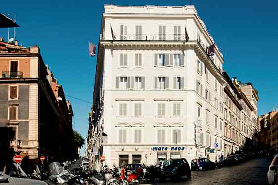 En gade med biler og motorcykler foran bygninger i byområdet. (AI-genereret tekst)