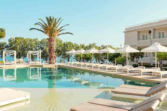 En pool med liggestole og parasoller ved et hotel med havudsigt. (AI-genereret tekst)