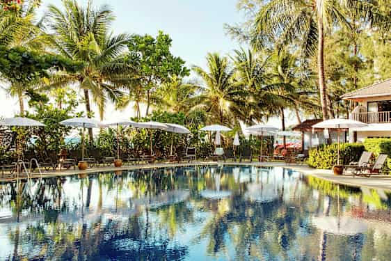 Udendørs pool omgivet af liggestole og parasoller, med palmer i baggrunden. (AI-genereret tekst)