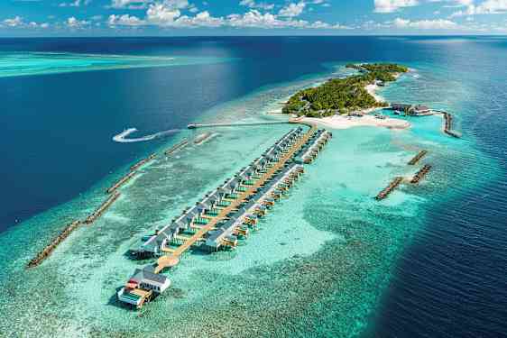 Luftfoto af en tropisk ø med strandvillaer i vandet og omgivet af turkis hav. (AI-genereret tekst)