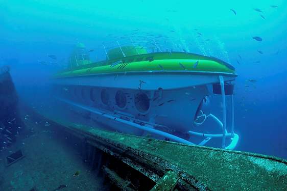 Et undervandsbillede af en ubåd nær et skibsvrag, omgivet af fisk. (AI-genereret tekst)