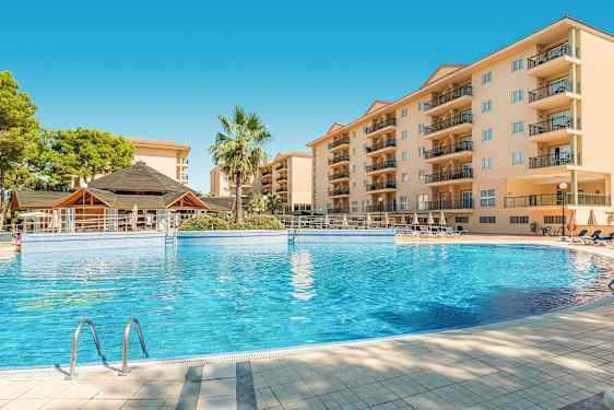 Billede af en hotelpool med omkringliggende bygninger og en palme. (AI-genereret tekst)