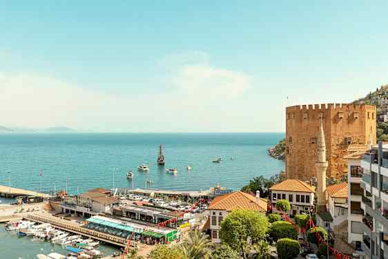 Et kystområde med en historisk borg, havn og bygninger. (AI-genereret tekst)