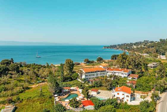 Landskabsbillede som viser bygninger med røde tage nær en kystlinje med havudsigt. (AI-genereret tekst)