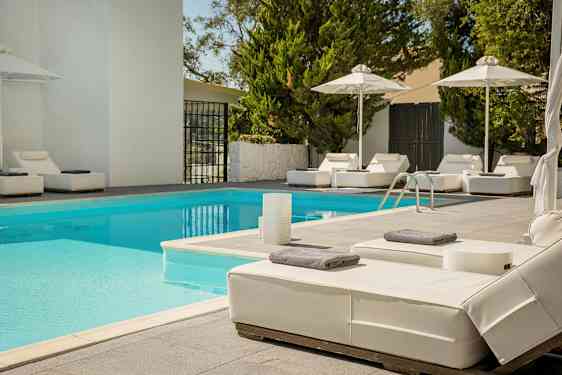 Udendørs pool med liggestole og parasoller. (AI-genereret tekst)