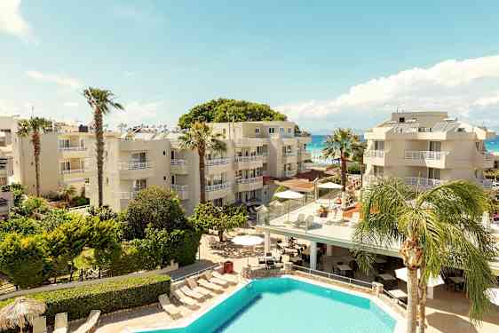 Et hotelområde med pool, palmer og bygninger tæt på havet. (AI-genereret tekst)