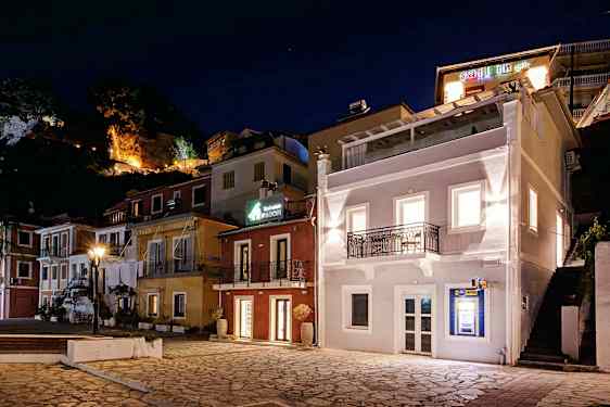 Torv med flerfarvede bygninger og belysning i aftenmørke. (AI-genereret tekst)