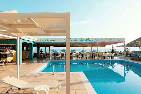 Billede af en pool ved en terrasse med restauranter ved havet. (AI-genereret tekst)