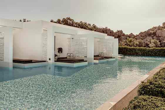 Udendørs swimmingpool med afgrænsede solsengeområder. (AI-genereret tekst)