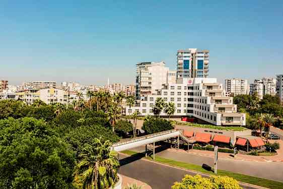 En moderne bygning omgivet af frodige træer og bymiljø. (AI-genereret tekst)