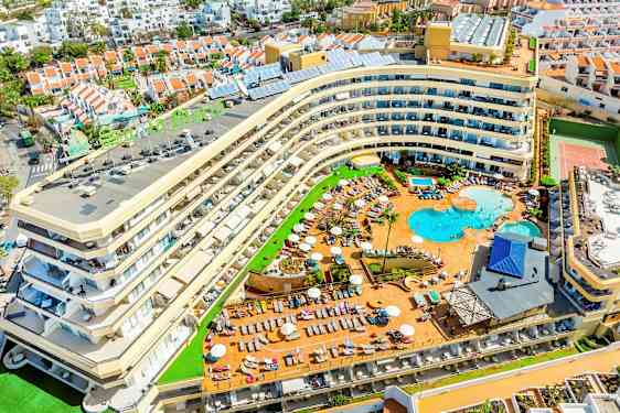 Billede af et hotel med poolområde og omkringliggende ferieboliger. (AI-genereret tekst)