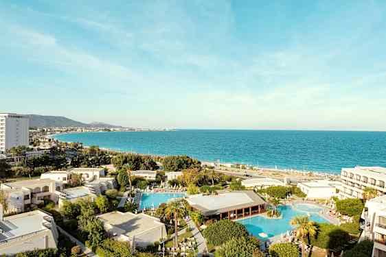 Udsigt over hotelområdet med swimmingpools og havet i baggrunden. (AI-genereret tekst)