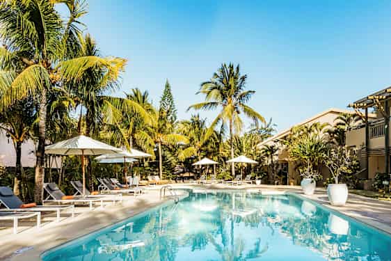 Poolområde med liggestole og parasoller, omgivet af palmer. (AI-genereret tekst)