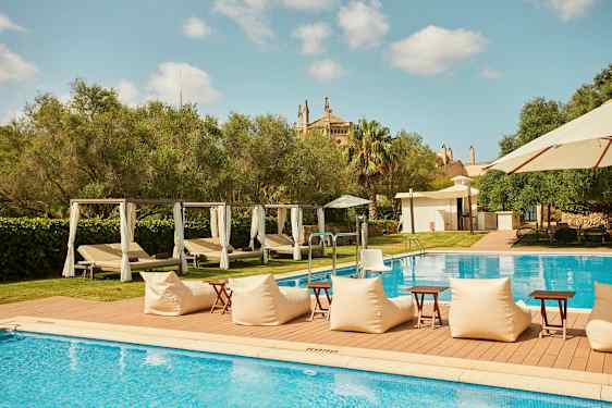 Udendørs pool med liggestole og parasoller, omgivet af grønne områder. (AI-genereret tekst)