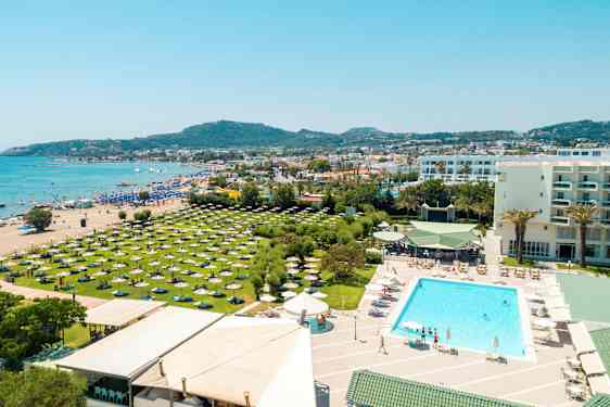 Postkort med udsigt over en strand, hotellets poolområde og grønne områder med parasoller. (AI-genereret tekst)