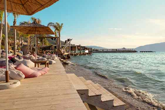 Liggestole og parasoller på en træbrygge ved vandet. (AI-genereret tekst)