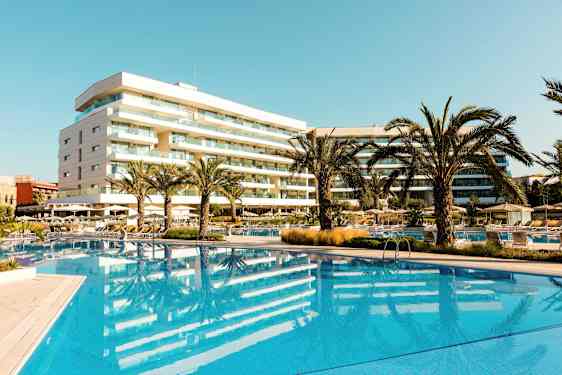 Hotel med pool og palmer i et solrigt område. (AI-genereret tekst)