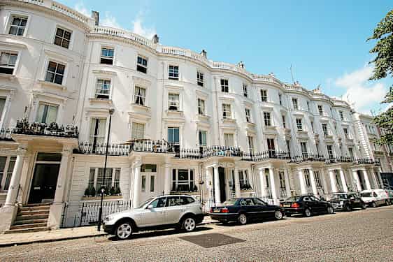 En række huse med hvide facader og parkerede biler foran. (AI-genereret tekst)