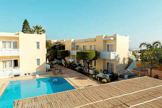 Gule bygninger omkring en pool med udendørsmøbler og parasoller. (AI-genereret tekst)