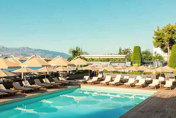 En udendørs swimmingpool omgivet af liggestole og parasoller. (AI-genereret tekst)