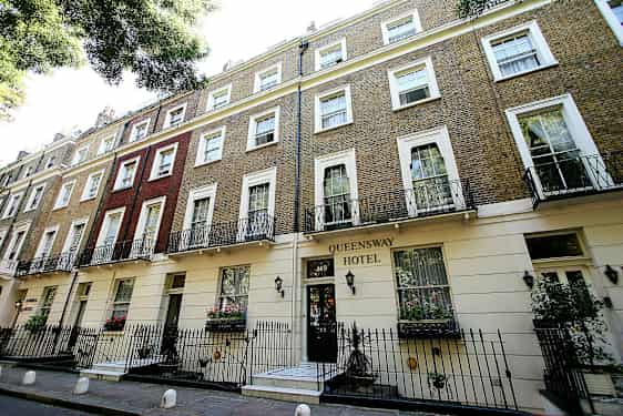Billede af bygningen Queensway Hotel med murværk og altaner. (AI-genereret tekst)