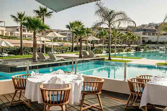 Et dækket bord ved en pool på et hotelområde. (AI-genereret tekst)