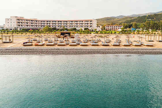 Strand med liggestole og parasoller foran et hotel. (AI-genereret tekst)