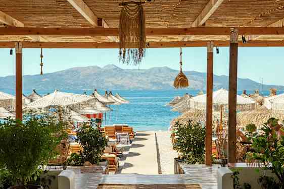 Strandudsigt med parasoller, liggestole og havet i baggrunden. (AI-genereret tekst)