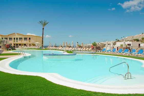 En pool ved et hotel omgivet af liggestole og parasoller. (AI-genereret tekst)