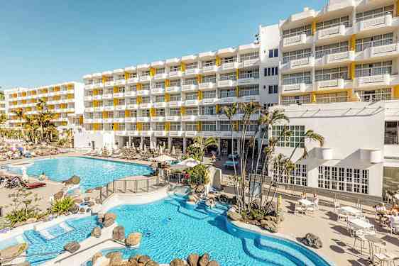 Hotelbygning med liggestole og poolområde. (AI-genereret tekst)