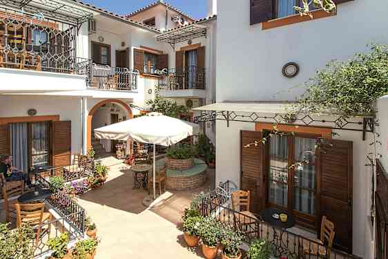 Indre gårdhave med café og blomsterkrukker. (AI-genereret tekst)