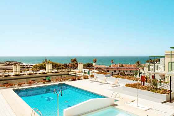 Billede af en pool og solterrasse med havet i baggrunden. (AI-genereret tekst)