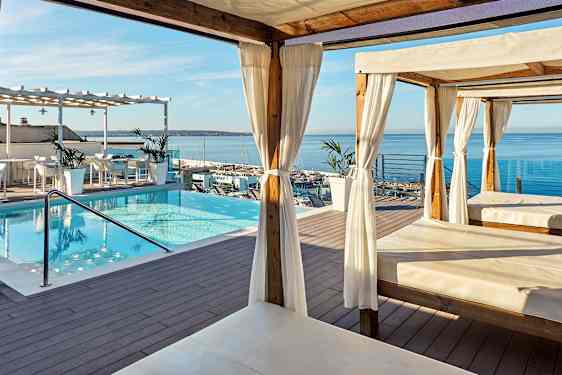 Terrasse med pool, cabanas og udsigt over havet. (AI-genereret tekst)