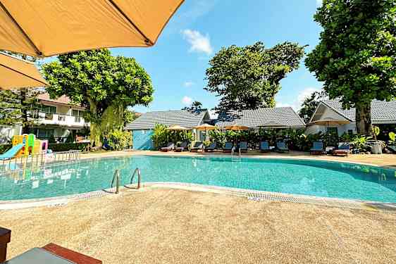 Udendørs pool med liggestole og en legeplads i baggrunden. (AI-genereret tekst)