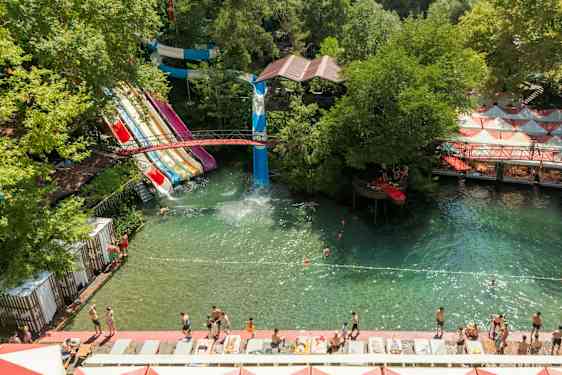 Vandpark med flere vandrutsjebaner og badeområde omgivet af grønne områder. (AI-genereret tekst)