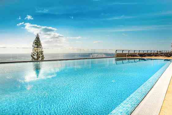 Tagpool med klart blå vand og udsigt mod himmel og træ. (AI-genereret tekst)