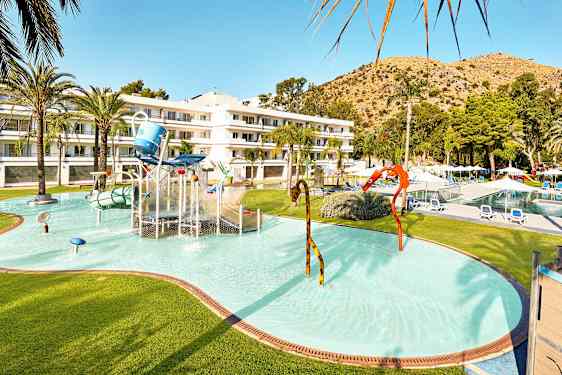 Børnepool med vandleg og hotelbygning i baggrunden. (AI-genereret tekst)