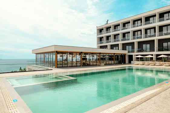 Et hotel med moderne poolområde og havudsigt. (AI-genereret tekst)