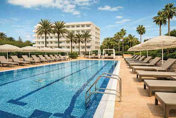 En hotelpool omgivet af liggestole og parasoller med en bygning i baggrunden. (AI-genereret tekst)