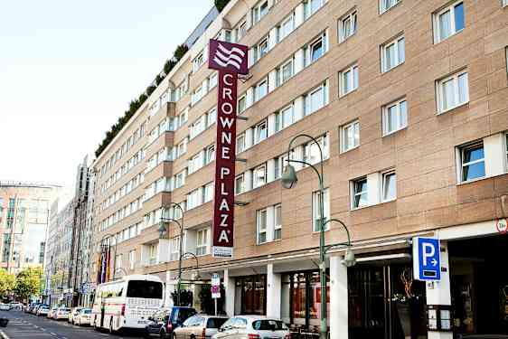 Crowne Plaza-hotelbygning med parkeringsskilt og bus foran. (AI-genereret tekst)