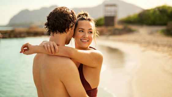 Par krammer hinanden på stranden